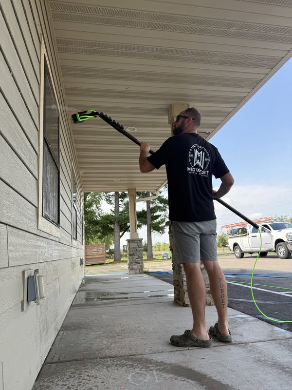 Midwest Power Washing technician cleaning exterior windows with a water-fed pole in Eau Claire WI